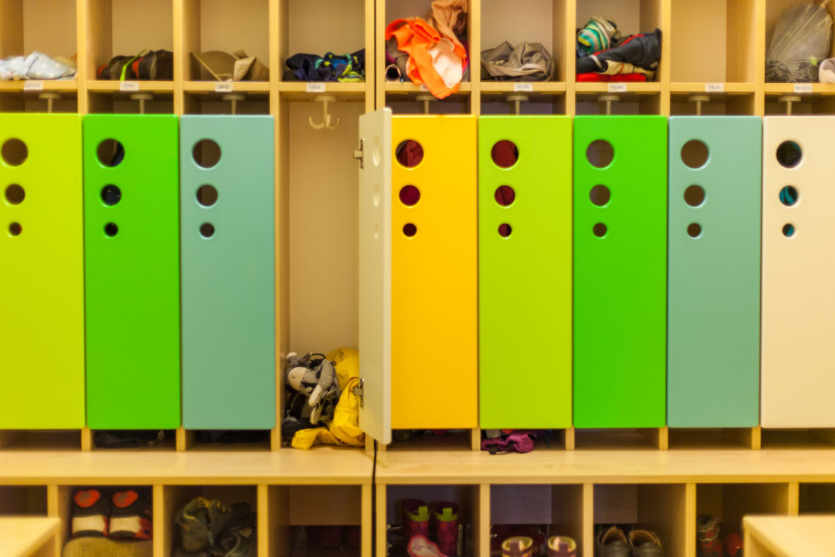 Bunte Kindergarderobe in Grün, Türkis, Gelb und Weiß mit Fächern für Kleidung und Schuhe.